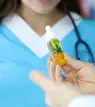 Vial with cannabis leaf image on it held in front of a medical professional