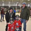 two adults standing with two kids on ice while public skating